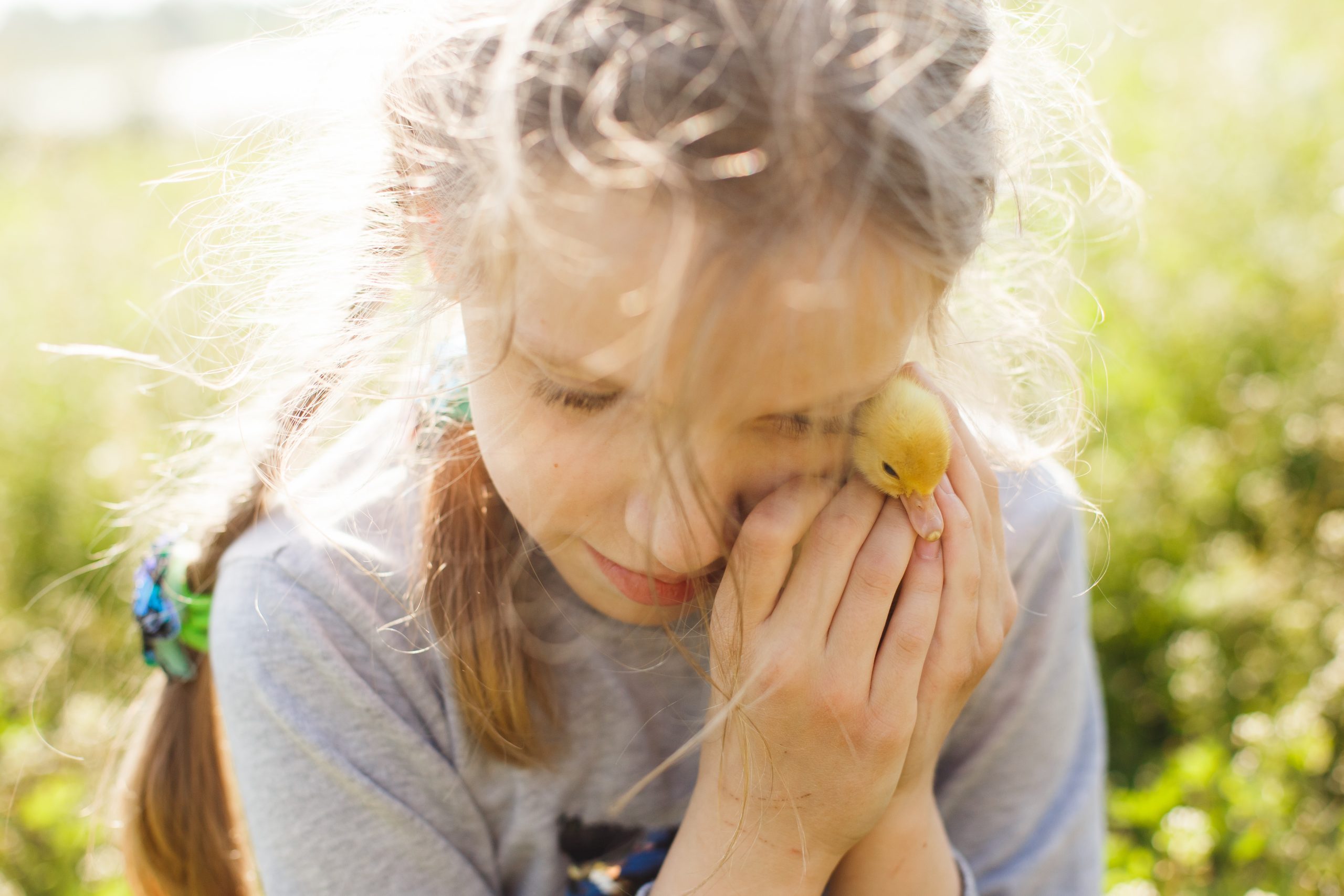 young girl holding a small toy duck near her face